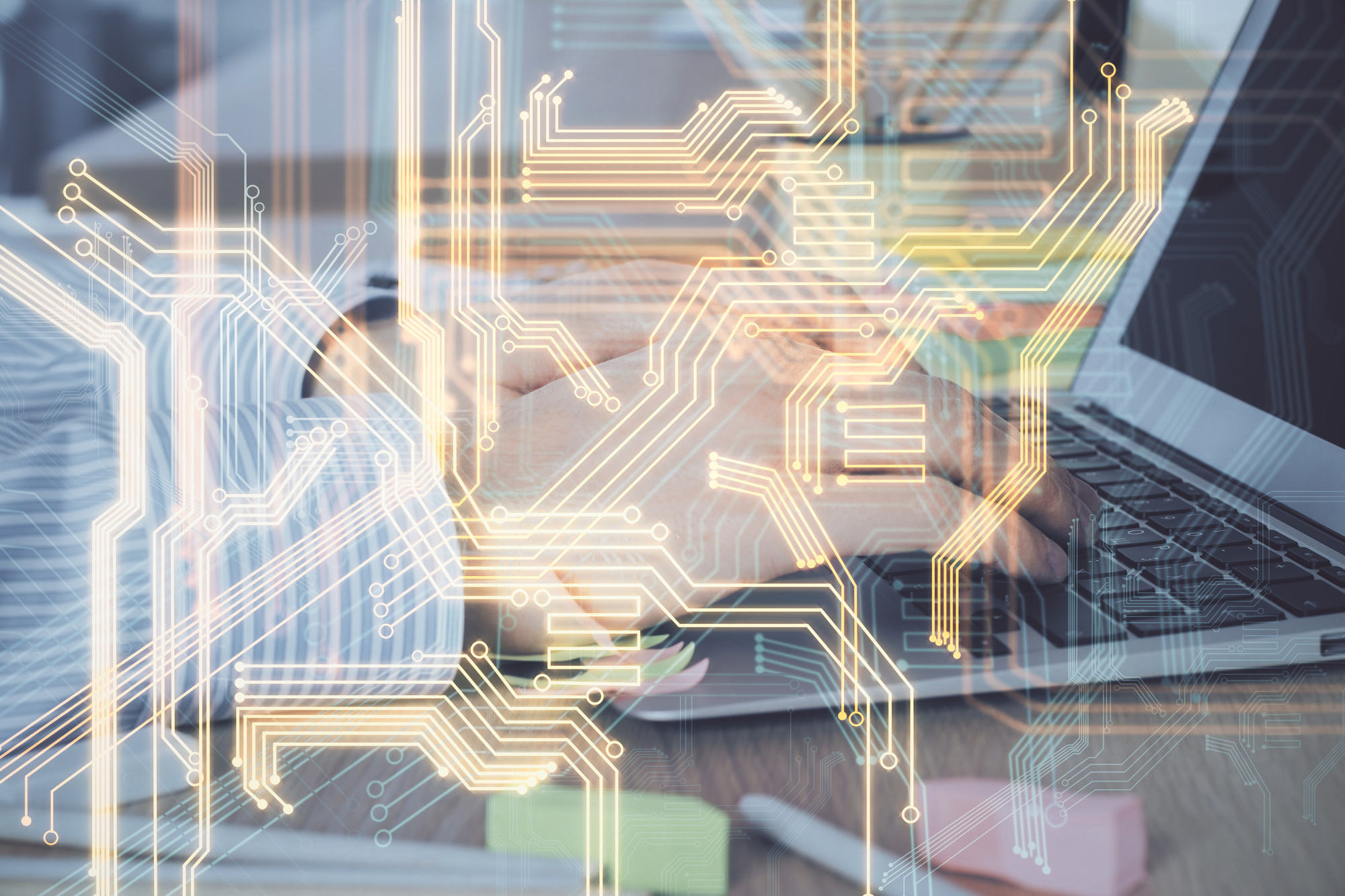 Circuit hologram against a closeup of a man working on a laptop