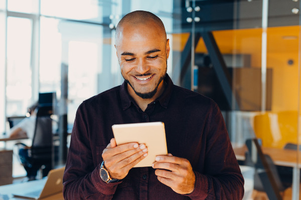 Smiling businessman looking at tablet in hands in a modern glass office