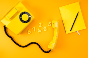 Vintage phone with notebook and numbers on yellow background