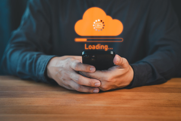 Person holding a smartphone with a glowing orange cloud upload icon and loading progress bar