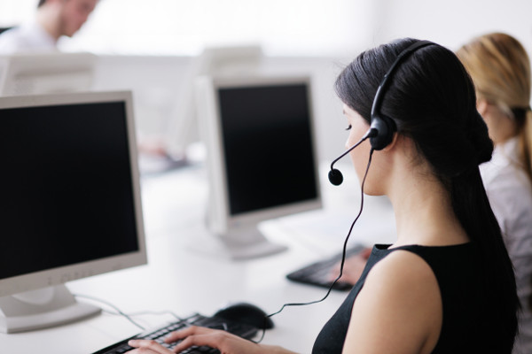 Support desk employees wearing headsets and working on computers
